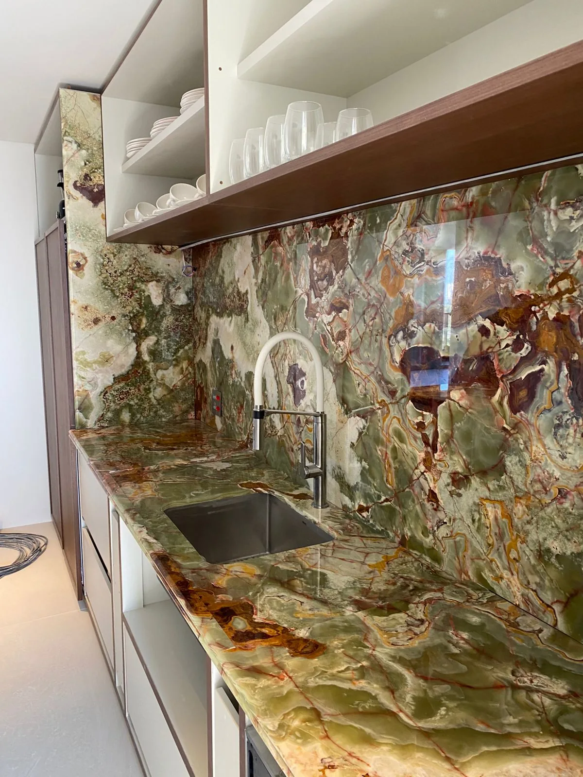 Bancada linear de cozinha em ônix verde polido com cuba de inox e frontão alto