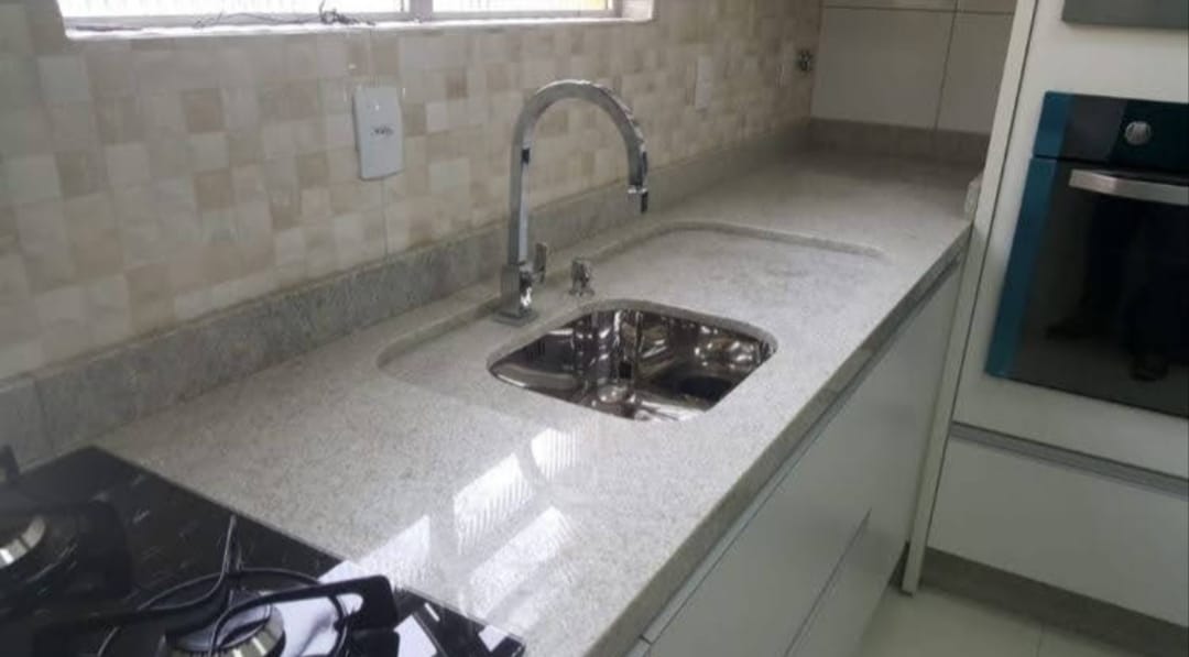 Bancada de cozinha em granito branco com cuba de inox e escorredor esculpido